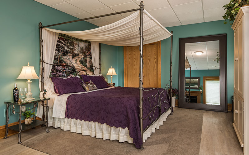 Stay at one of the best Baraboo WI hotels this fall. Image of four poster bed with purple bedspread.