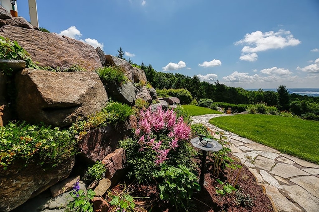 Inn at Wawanissee Point, Devils Lake Wisconsin, path leading to fire pit with pink flowers in foreground and trees and grass in the background.