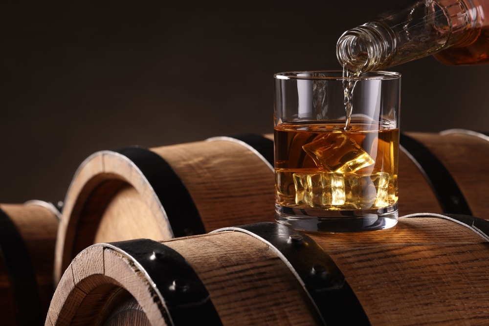 Visit the Driftless Glen Distillery for an exceptional drink and dinner. Whiskey being poured into a glass among some barrels of spirits.